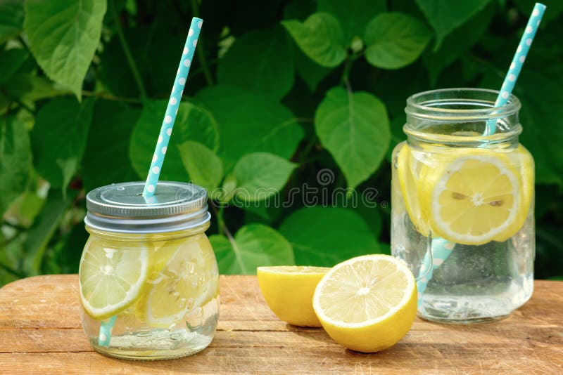 Deux pots de stand de limonade sur un support en bois Un fond d'un buisson vert dans une tache floue Dans le pot une paille est i photos stock Deux pots de stand de limonade sur un support en bois Un fond d'un buisson vert dans une tache floue Dans le pot une paille est i photos stock