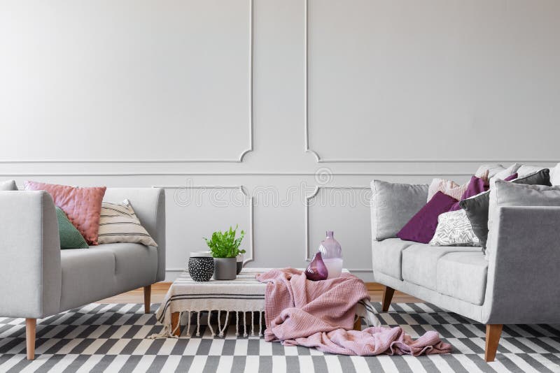 Deux sofas avec le sort des oreillers et de la table basse avec l'usine dans le pot, les vases en verre et des tasses de café dan photo stock Deux sofas avec le sort des oreillers et de la table basse avec l'usine dans le pot, les vases en verre et des tasses de café dan photo stock