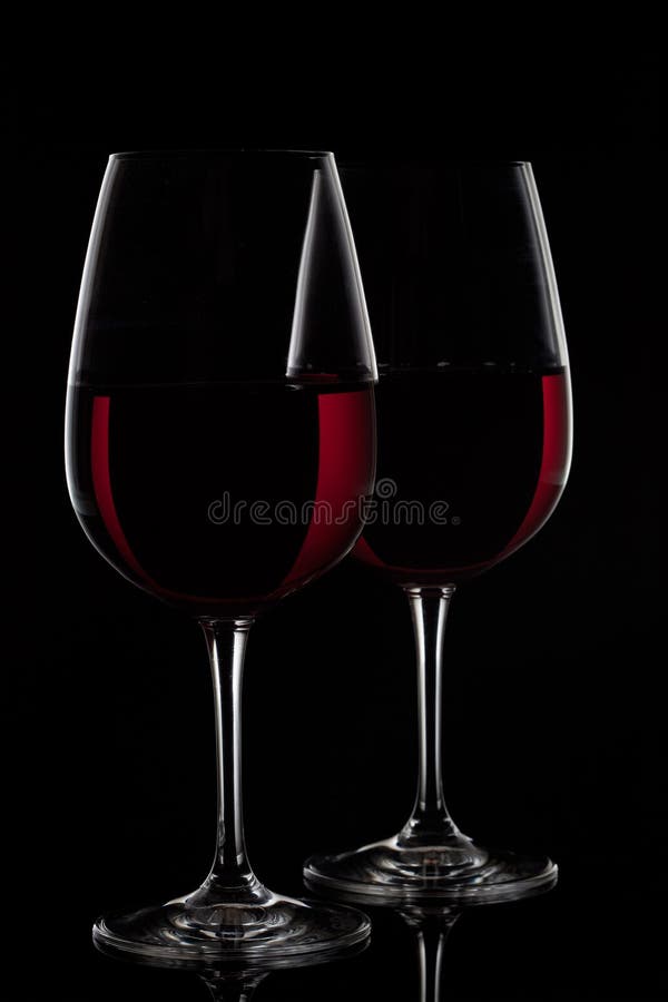 Deux verres de vin rouge avec du vin sur le fond noir image stock Deux verres de vin rouge avec du vin sur le fond noir image stock