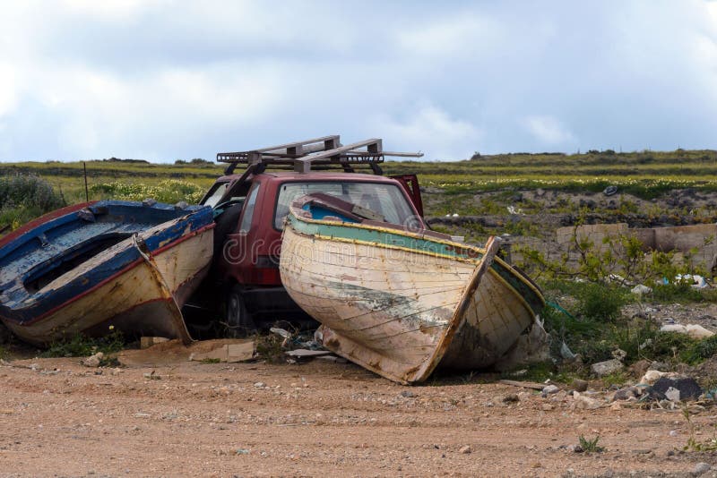 Deux vieux bateaux de pêche abandonnés et une voiture détruite rouge dans une décharge de déchets Choses abandonn?es transport photo libre de droits Deux vieux bateaux de pêche abandonnés et une voiture détruite rouge dans une décharge de déchets Choses abandonn?es transport photo libre de droits