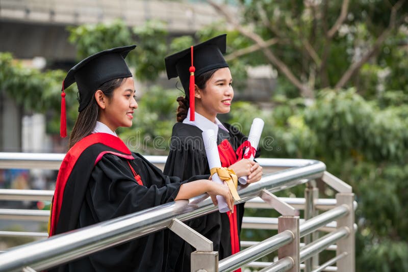 Deux étudiants asiatiques féminins de sourire dans la robe d'obtention du diplôme photo libre de droits Deux étudiants asiatiques féminins de sourire dans la robe d'obtention du diplôme photo libre de droits