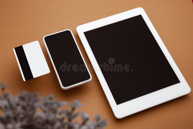 Devices with blank screens floating above brown background. Phone, tablet, card. Office styled, modern mockup for advertising, image or text. Blank white copyspace for design, business and finance concept. Devices with blank screens floating above brown background. Phone, tablet, card. Office styled, modern mockup for advertising, image or text. Blank white copyspace for design, business and finance concept.