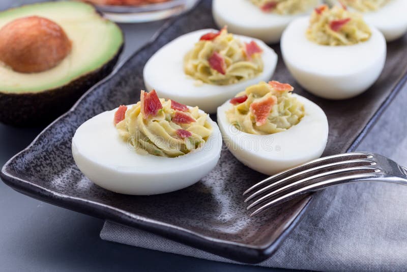 Deviled Eggs Stuffed with Avocado, Egg Yolk and Mayonnaise Filling, Garnished with Bacon