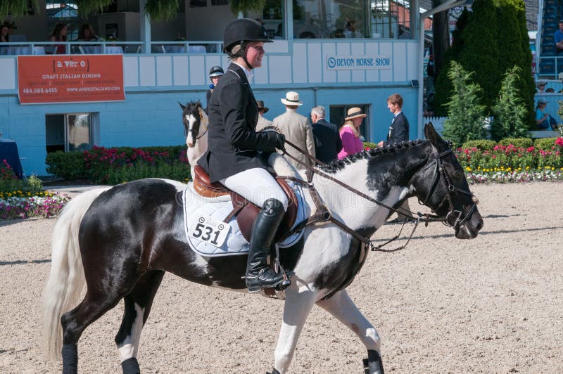 DEVON, PA - 25 MAI : Cavaliers exécutant avec leurs chevaux chez Devon Horse Show le 25 mai 2014 photographie stock libre de droits DEVON, PA - 25 MAI : Cavaliers exécutant avec leurs chevaux chez Devon Horse Show le 25 mai 2014 photographie stock libre de droits