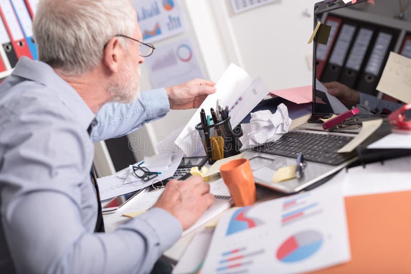 Dezorganizujący biznesmen patrzeje dla dokumentów zdjęcia stock Dezorganizujący biznesmen patrzeje dla dokumentów zdjęcia stock
