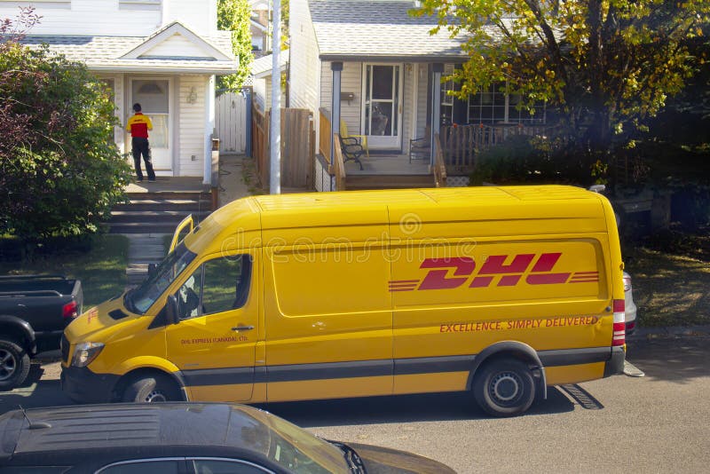 A DHL Worker Delivering a Package at Front Door of a House Editorial