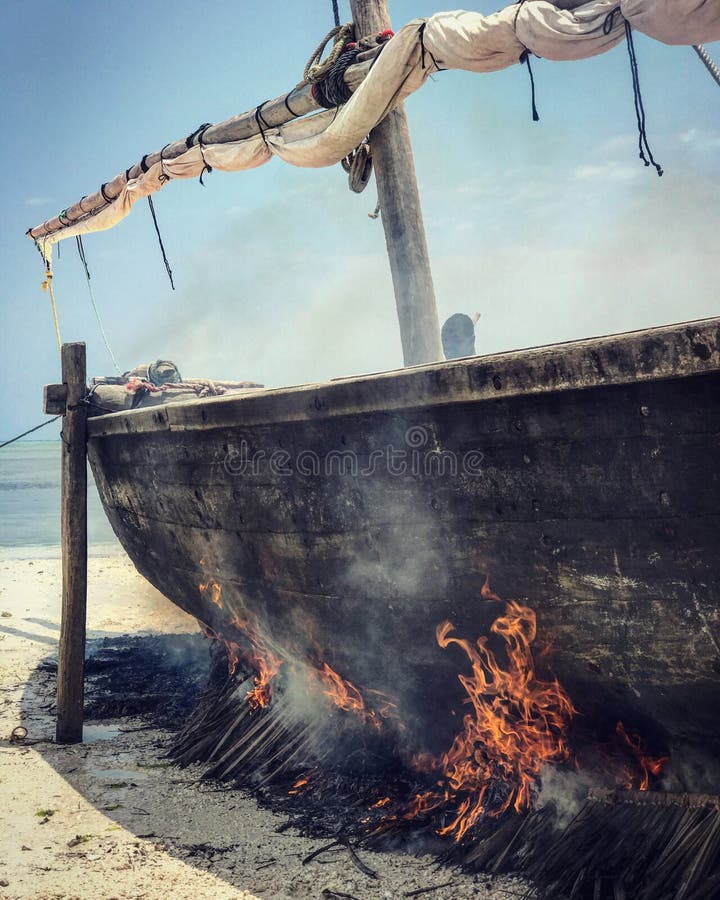 A man burns a dhow in the shores of Zanzibar, Tanzania royalty free stock photography A man burns a dhow in the shores of Zanzibar, Tanzania royalty free stock photography