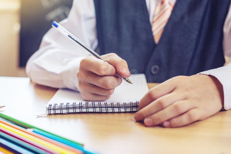 Di nuovo al banco Bambino sveglio che si siede allo scrittorio nell'aula Il ragazzo sta imparando che le lezioni scrive una penna fotografie stock libere da diritti Di nuovo al banco Bambino sveglio che si siede allo scrittorio nell'aula Il ragazzo sta imparando che le lezioni scrive una penna fotografie stock libere da diritti