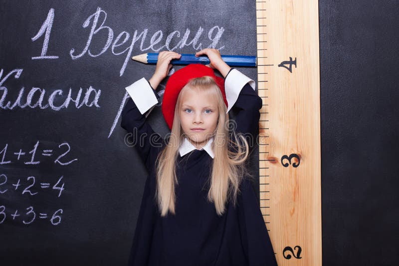 Di nuovo a scuola! La scolara è alla lavagna con un righello La scolara risponde alla lezione Primo selezionatore vicino al bordo fotografia stock libera da diritti Di nuovo a scuola! La scolara è alla lavagna con un righello La scolara risponde alla lezione Primo selezionatore vicino al bordo fotografia stock libera da diritti