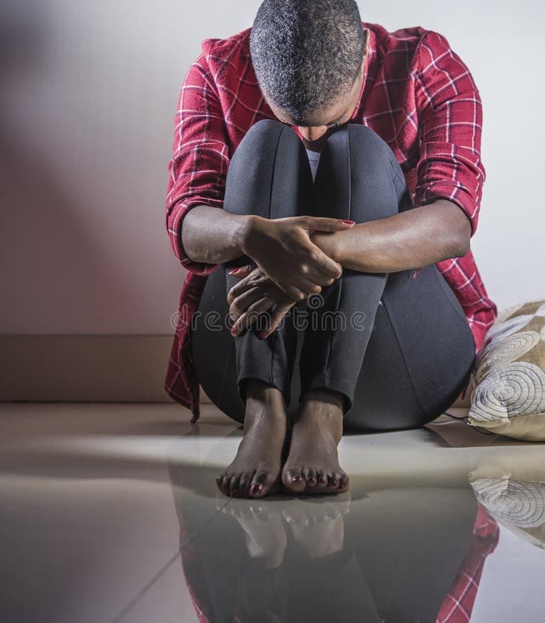 Lifestyle indoors shady portrait of young sad and depressed black african American woman sitting at home floor feeling desperate and worried suffering pain and depression in dramatic light. Lifestyle indoors shady portrait of young sad and depressed black african American woman sitting at home floor feeling desperate and worried suffering pain and depression in dramatic light