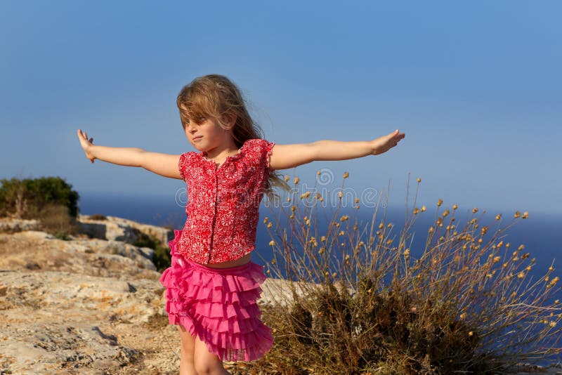 Blue day with kid girl open hands to the wind and Mediterranean sea. Blue day with kid girl open hands to the wind and Mediterranean sea