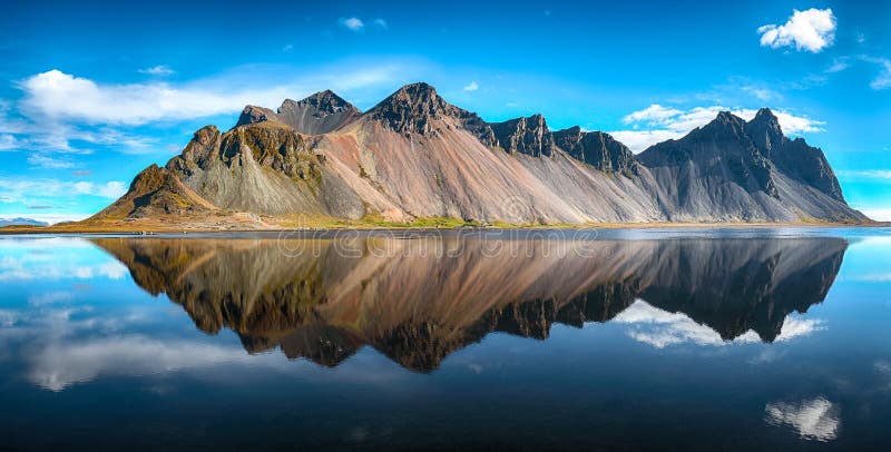 Dia ensolarado esplêndido e reflexão lindo do mountaine de Vestrahorn no cabo de Stokksnes em Islândia