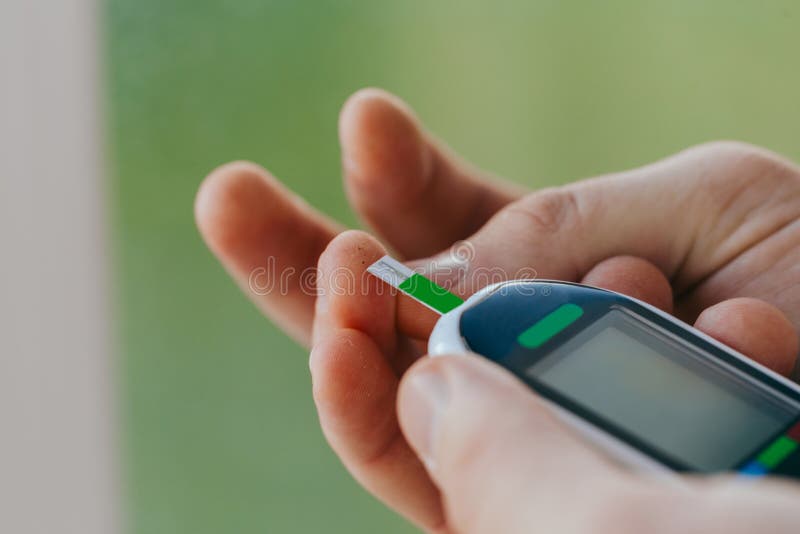 Diabetes, healthcare - close up of a man with a glucometer and a test strip checking blood sugar at home. Medicine, diabetes, glycemia, healthcare and people