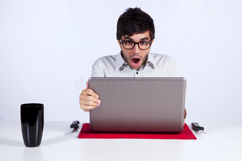 Young man shocked with something he see on his laptop computer. Young man shocked with something he see on his laptop computer