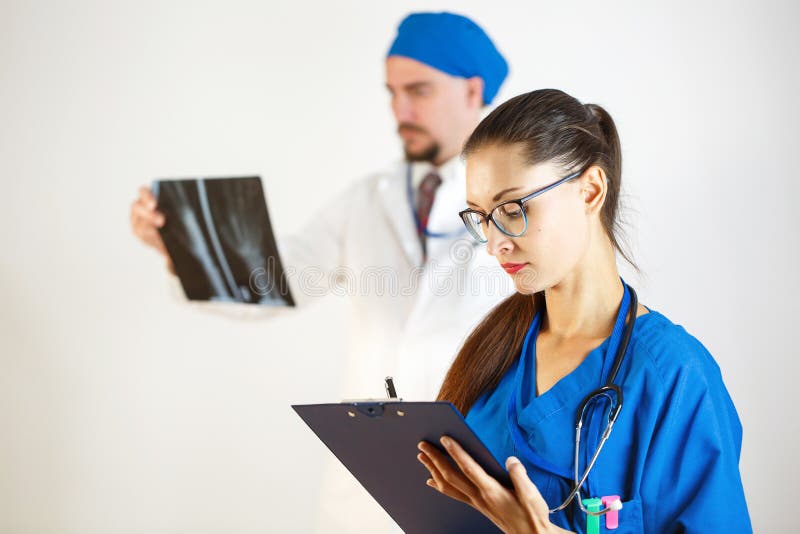 Diagnostics with the help of X-rays, two doctors look at the results, the doctor takes notes to the card. White background stock image Diagnostics with the help of X-rays, two doctors look at the results, the doctor takes notes to the card. White background stock image