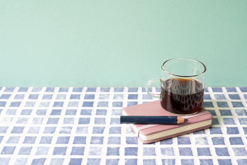 Diary notebook, pencil, coffee on blue tile desk. mint wall background. workspace. studio shot