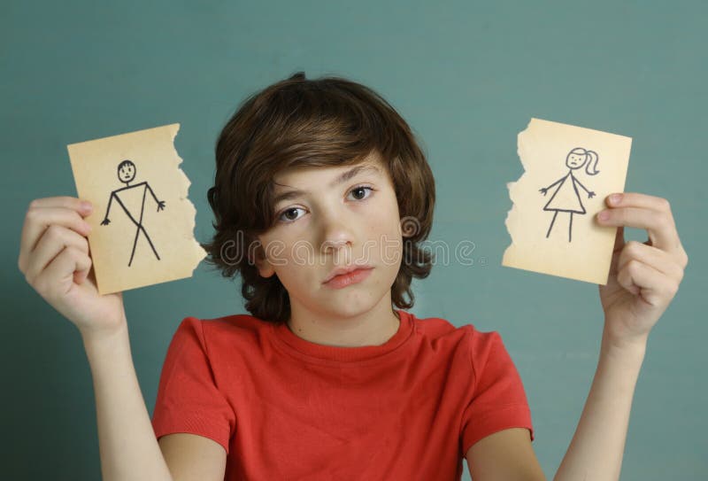 Teenager boy hold mom and dad drawing in two torn paper pieces as a symbol of divorce close up sad portrait. Teenager boy hold mom and dad drawing in two torn paper pieces as a symbol of divorce close up sad portrait