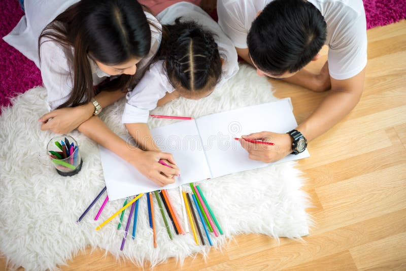 Dibujo joven de la familia así como los lápices coloridos en casa imagen de archivo libre de regalías Dibujo joven de la familia así como los lápices coloridos en casa imagen de archivo libre de regalías
