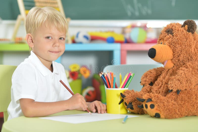 Dibujo lindo del niño pequeño con los lápices en sala de clase imagenes de archivo Dibujo lindo del niño pequeño con los lápices en sala de clase imagenes de archivo