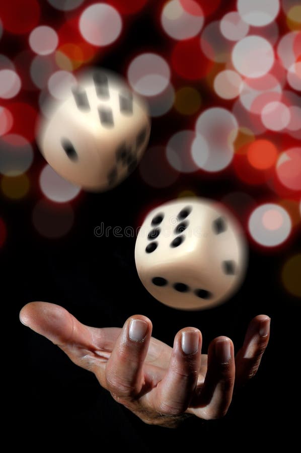 Hand throwing dice in a dark background.