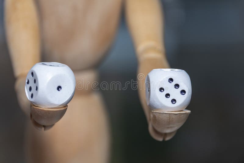 Dice in the hands of a wooden figurine close-up. Concept: chances and luck, lottery, choice royalty free stock images Dice in the hands of a wooden figurine close-up. Concept: chances and luck, lottery, choice royalty free stock images