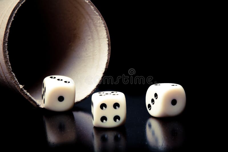Dice on old wood black table near a container