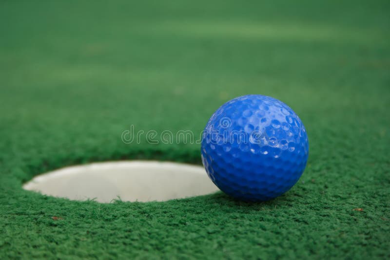 A miniature golf ball near the hole. A miniature golf ball near the hole