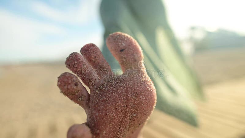 Dichtslibben van voetjes en tenen in het zand van een jong meisje in langzame beweging. kronkelt tenen op een zandig strand op een