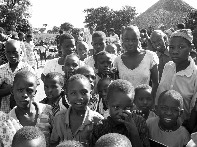 Die afrikanischen neugierigen Kinder der Menge, die als Hilfsmitarbeiter einer hilfsorganisation zusammentreten, kommen an