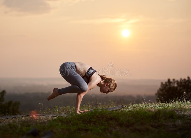 Die attraktive dünne junge Frau, die Yoga tut, trainiert draußen auf Kopienraumhintergrund des schönen Himmels lizenzfreie stockfotos Die attraktive dünne junge Frau, die Yoga tut, trainiert draußen auf Kopienraumhintergrund des schönen Himmels lizenzfreie stockfotos
