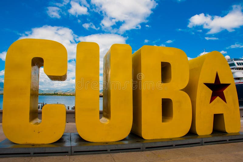 The inscription of the CUBA. Huge letters on the waterfront, against a blue sky with clouds in Santiago de Cuba. The inscription of the CUBA. Huge letters on the waterfront, against a blue sky with clouds in Santiago de Cuba