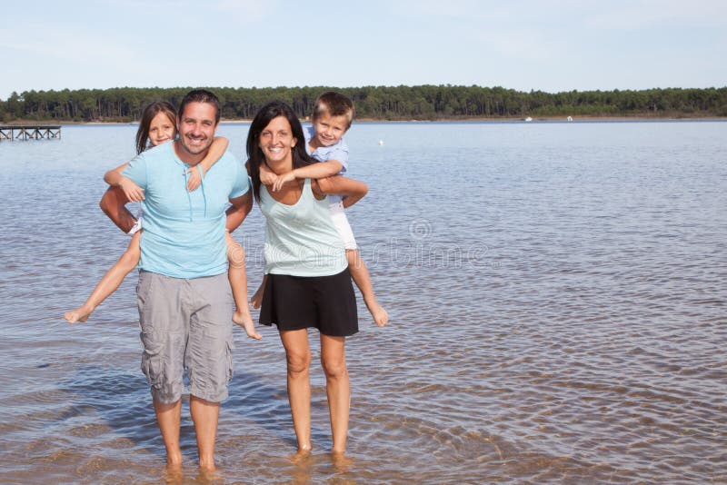 Die Familie, die entlang Sandy Beach-Eltern geht, haben die Kinder lizenzfreies stockfoto Die Familie, die entlang Sandy Beach-Eltern geht, haben die Kinder lizenzfreies stockfoto