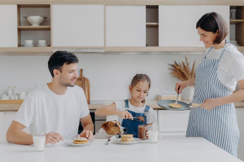 Die Familie frühstückt morgens in der Küche Happy Girl legt geschmolzene Schokolade auf leckeren frittierten Pfannkuchen, Posen a stockfoto Die Familie frühstückt morgens in der Küche Happy Girl legt geschmolzene Schokolade auf leckeren frittierten Pfannkuchen, Posen a stockfoto