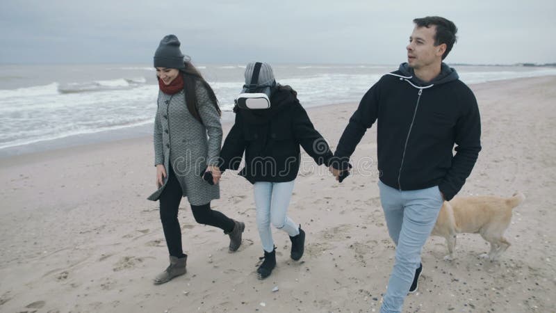 Die Familie geht entlang den Strand, und das Kind wird in der virtuellen Welt untergetaucht Punkte von VR auf der Tochter während