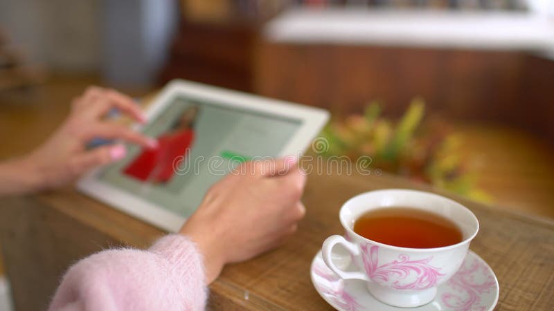 Die Frau, die an ihrem Schreibtisch mit dem Tablet-Computer sitzt, betrachtet on-line-Kleinbekleidungsgeschäftwebsite Standort ze