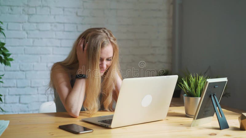 Die Frau am Laptopumkippen, der Ausfall des Geschäfts, bestand nicht die Prüfung, ergreift seinen Kopf