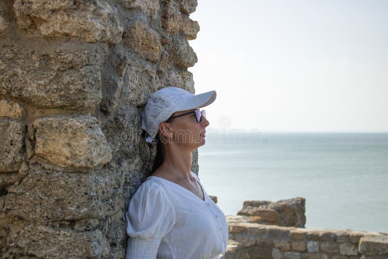 Die Frau in weißer Bluse im Hintergrund der defensiven Steinwände. stockfotografie