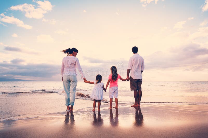 Die glückliche Familie haben Spaß gehend auf Strand bei Sonnenuntergang