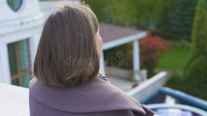 Die glückliche Frau, die auf Balkon des Zustandes, atmende Frischluft steht, sicherte das Leben