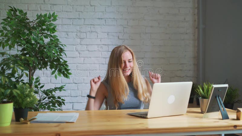 Die glückliche Frau, die aufgeregt glaubt, den Laptopschirm betrachtend, der am Arbeitsplatz sitzt, feiert Geschäftserfolg, on-li
