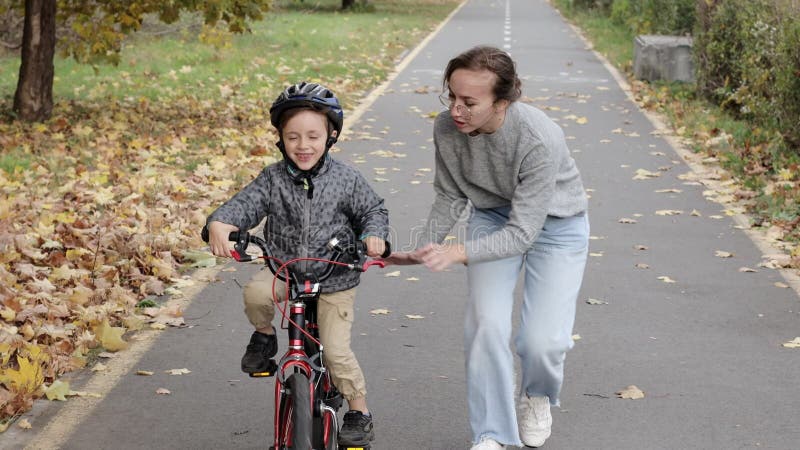 Die glückliche Mutter lehrt den Sohn, Fahrrad zu fahren