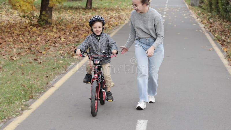 Die glückliche Mutter lehrt den Sohn, Fahrrad zu fahren