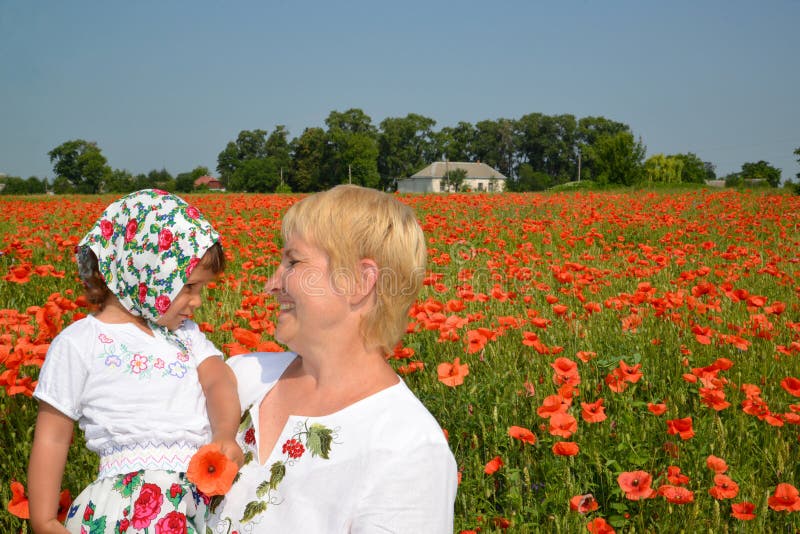 Die Großmutter und der Enkelinblick auf einander mitten in einem Mohnblumenfeld stockfotografie Die Großmutter und der Enkelinblick auf einander mitten in einem Mohnblumenfeld stockfotografie