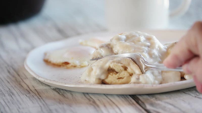 Die Hand der Frau mithilfe einer Gabel in Buttermilchkekse -soße zu senken..