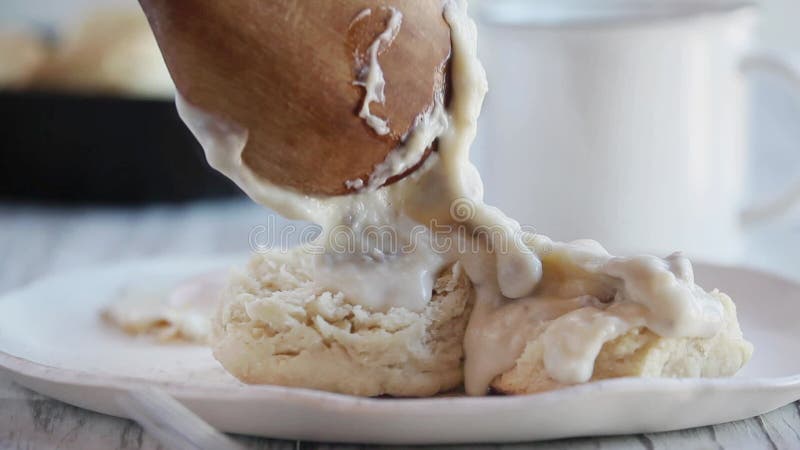 Die Hand der Frau mithilfe eines Löffels, um die Hot Soße über Buttermilchkeksen zu pumpen.