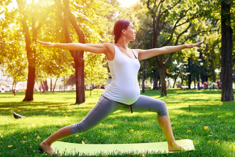 Die harmonische schwangere Frau, die im Yoga meditiert, werfen draußen auf stockfoto Die harmonische schwangere Frau, die im Yoga meditiert, werfen draußen auf stockfoto