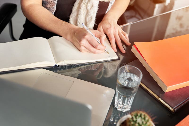 Die Hände der Frau, die Anmerkungen auf weißem verbreitetem Notizbuch machen Kaktus und Glas Wasser Junge Frau oder Student, die stockbilder
