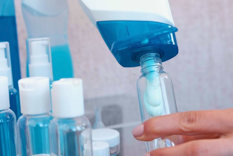 Die Hände der Frau gießen blaues Shampoo in einer kleinen Flasche von großem Reisesatz Gläser Flaschennahaufnahme stockbild Die Hände der Frau gießen blaues Shampoo in einer kleinen Flasche von großem Reisesatz Gläser Flaschennahaufnahme stockbild