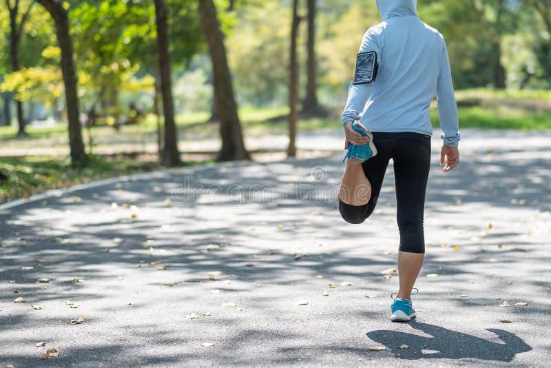 Die junge Athletenfrau, die im Park im Freien, weiblicher Läufer streching ist, wärmen bereites zu auf der Straße draußen rütteln