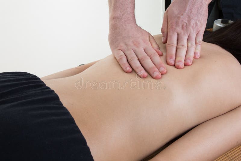Die junge Frau, die auf einer Massagetabelle liegt und wird massiert lizenzfreies stockbild Die junge Frau, die auf einer Massagetabelle liegt und wird massiert lizenzfreies stockbild